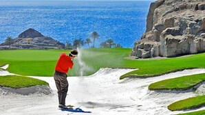 A person playing golf on a course with a view of the ocean and rocky cliffs. - Cozy apartment with sea views, Playa del Cura, Jardin Paraiso  (MOGAN)