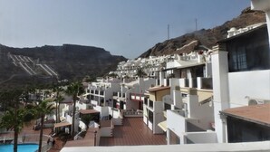 A resort with white buildings, a swimming pool, and a mountainous backdrop. - Cozy apartment with sea views, Playa del Cura, Jardin Paraiso  (MOGAN)