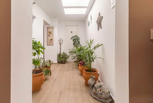 A hallway with potted plants, a trident, and a snail sculpture.
