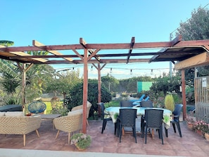 A covered outdoor patio with wicker furniture, a table, and chairs.