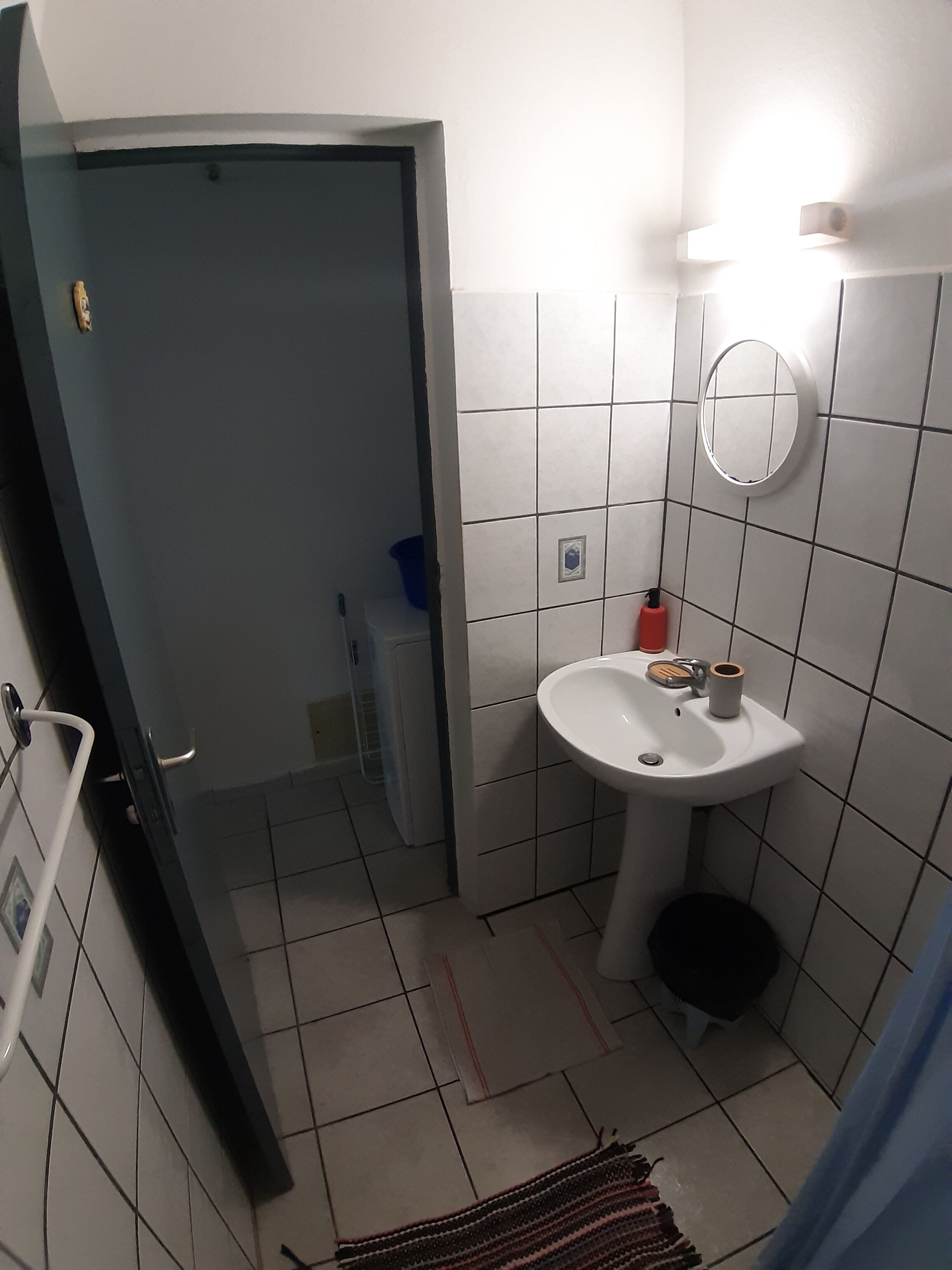 A bathroom with a white sink, a mirror, and a toilet.