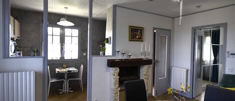 Ein Essbereich mit Kamin, Deckenventilator und Blick in einen anderen Raum.