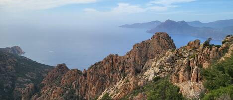 Un paysage montagneux caractérisé par un terrain rocheux et une vue sur la mer.
