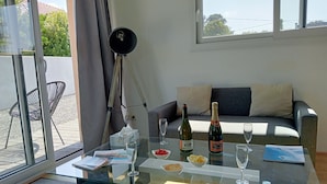 A modern living room with a glass coffee table, two bottles of champagne, and a bowl of cherries.