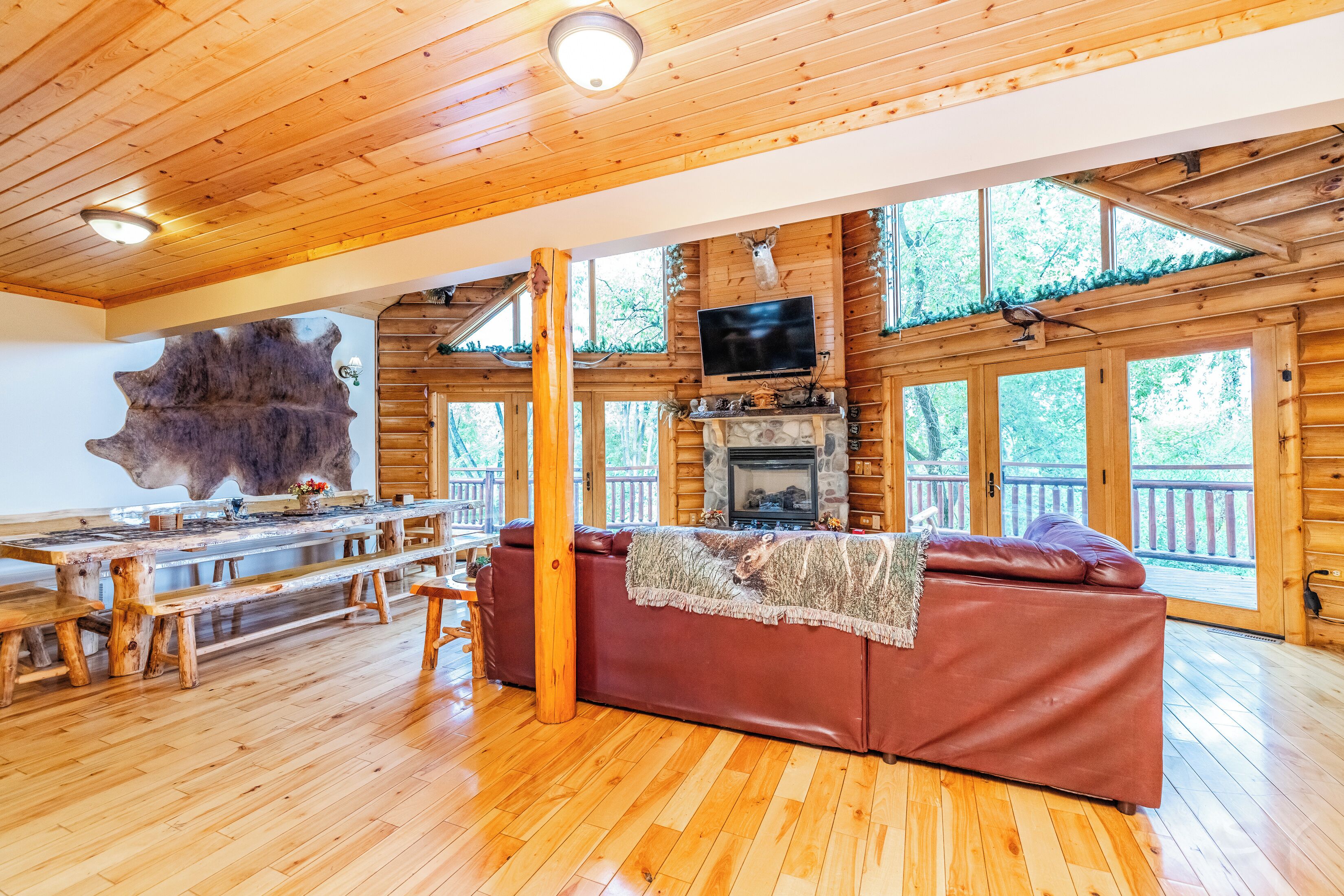 Un intérieur en bois avec une cheminée, un téléviseur et une grande table en bois.