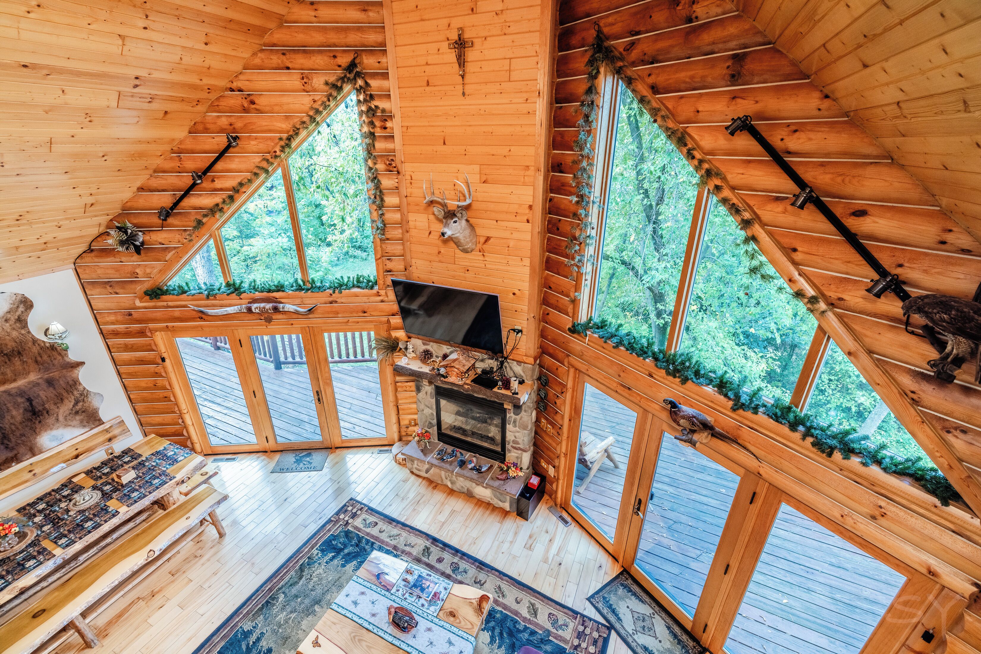L’intérieur d’une cabane en rondins, avec une cheminée, des bancs en bois et une grande fenêtre décorée d’une tête de cerf.