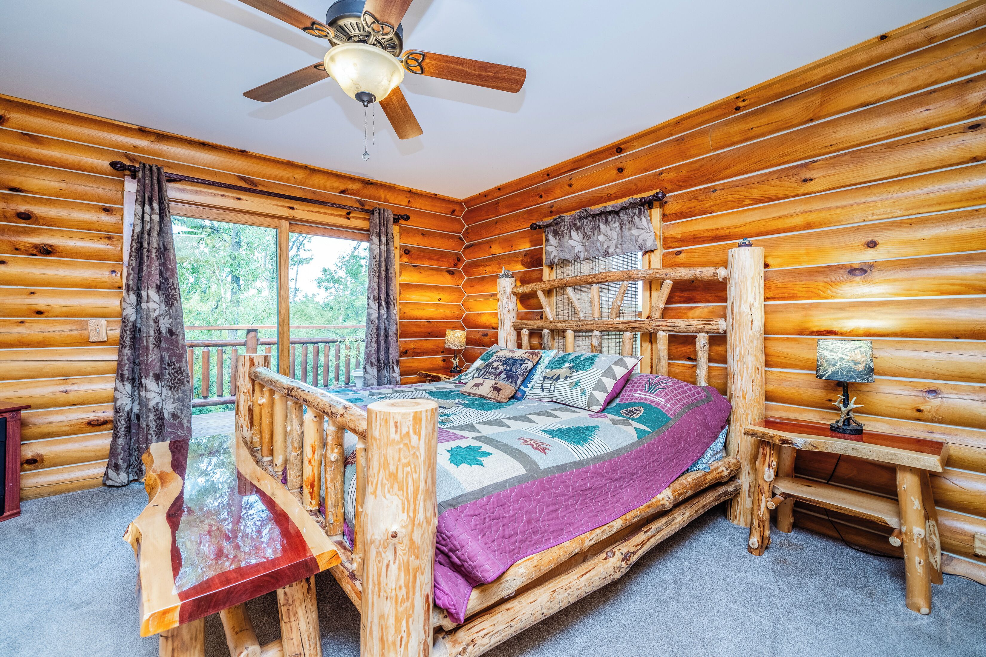 Quarto de cabana rústica com cama de madeira, ventilador de teto e janela com cortinas.