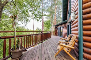 A wooden deck with a railing, a potted plant, and two wooden chairs. - Beautiful Log Cabin Near Devil’s Lake (baraboo)