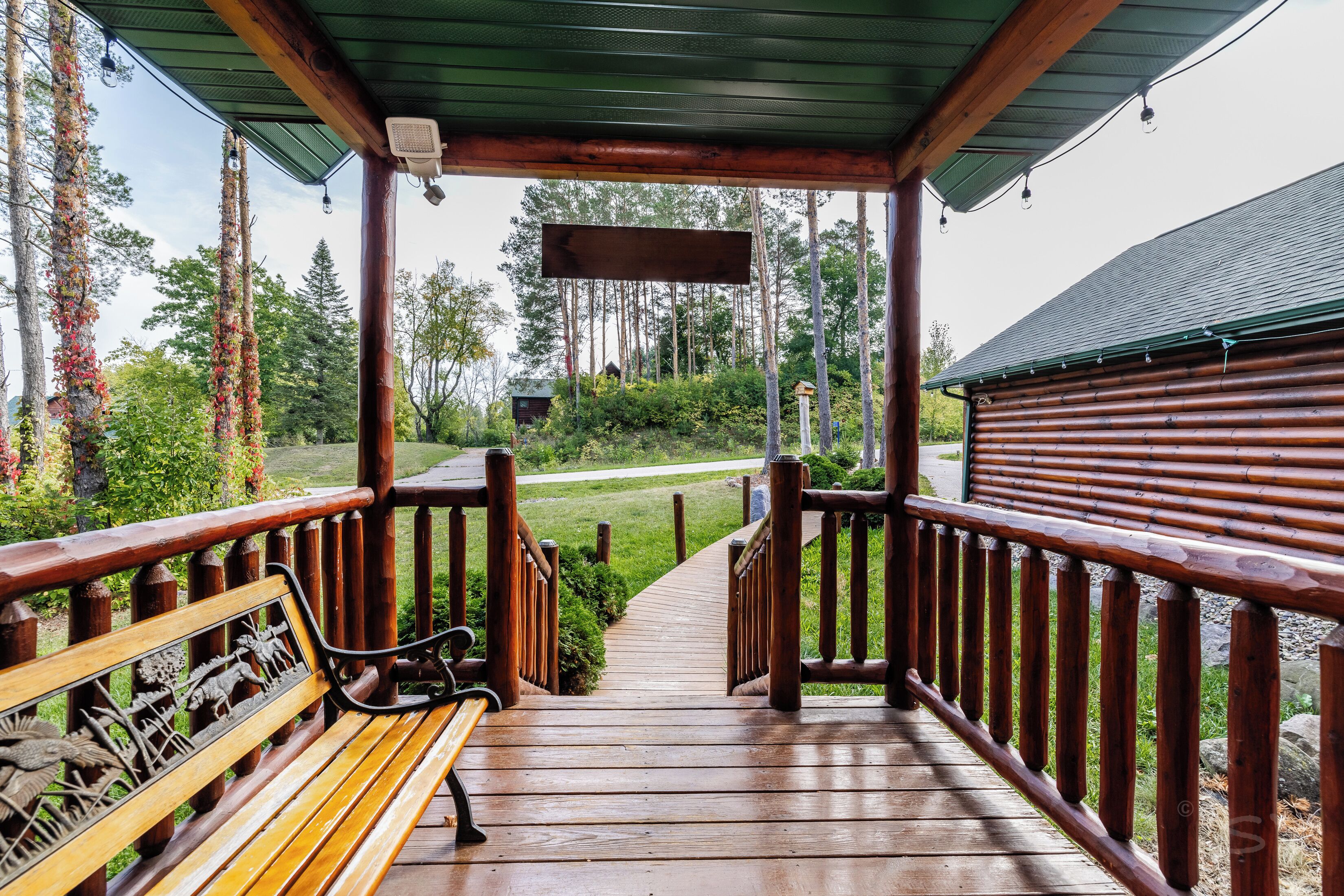 A wooden deck with a bench, a wooden railing, and a view of a forested area.