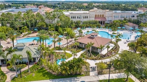Et resort med flere swimmingpools, palmer og en stor bygning i baggrunden.