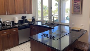 Une cuisine moderne avec des meubles en bois, un lave-vaisselle encastré et un grand îlot central doté d’un plan de travail en verre.