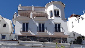 A multi-story building with balconies, a stone facade, and a clear blue sky.