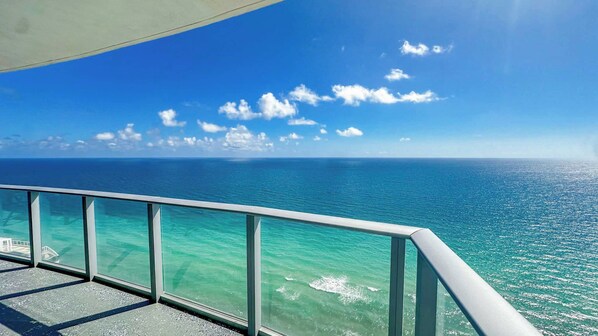 A clear view of the ocean from a balcony with a metal railing.
