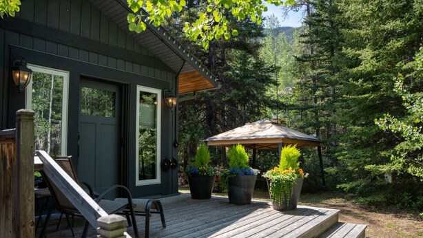 A wooden deck with outdoor seating, a covered patio area, and potted plants.
