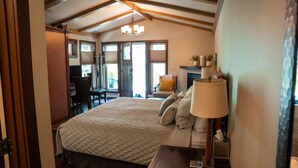 A bedroom with a large bed, a desk, and a chair. There is a window and a door leading to another room.