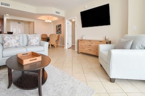 A modern living room with a sofa, a coffee table, and a TV mounted on the wall.