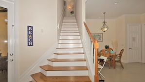 Eine Treppe mit Holzboden und weißen Geländern, die zu einem Essbereich mit Tisch und Stühlen führt.