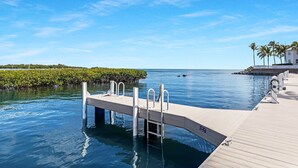 Un muelle de madera se adentra en aguas tranquilas bajo un cielo despejado.