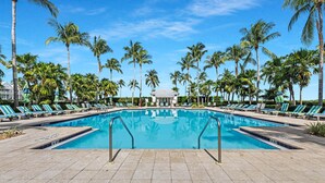 Una piscina con sillas de descanso y palmeras.