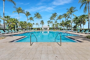 A swimming pool with lounge chairs and palm trees.