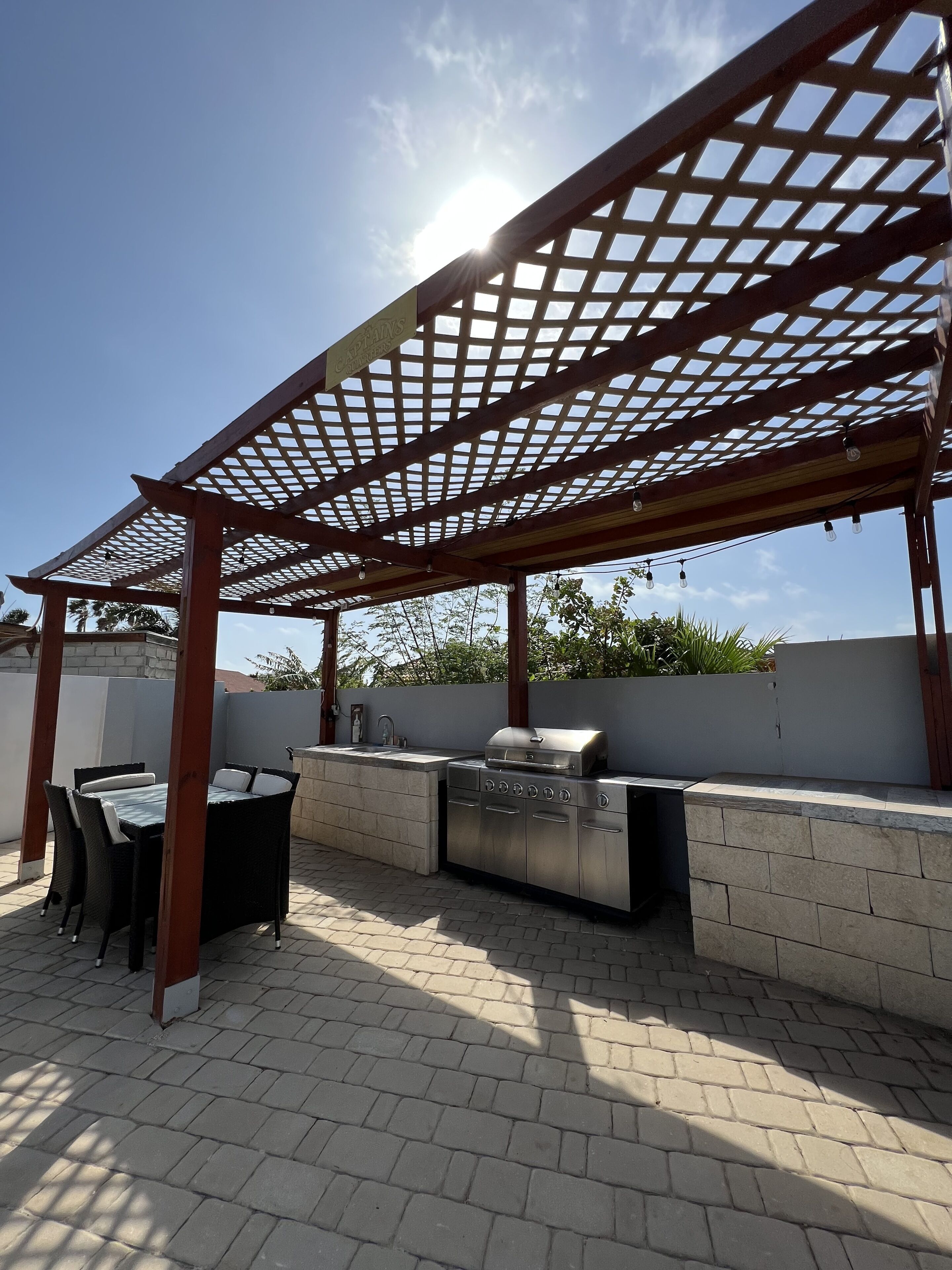 An outdoor patio with a grill, seating area, and a pergola structure.