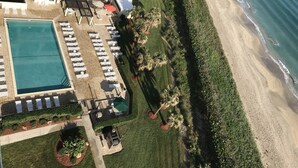 Oversigtsbillede af et resort med flere swimmingpools, liggestole og et strandområde.