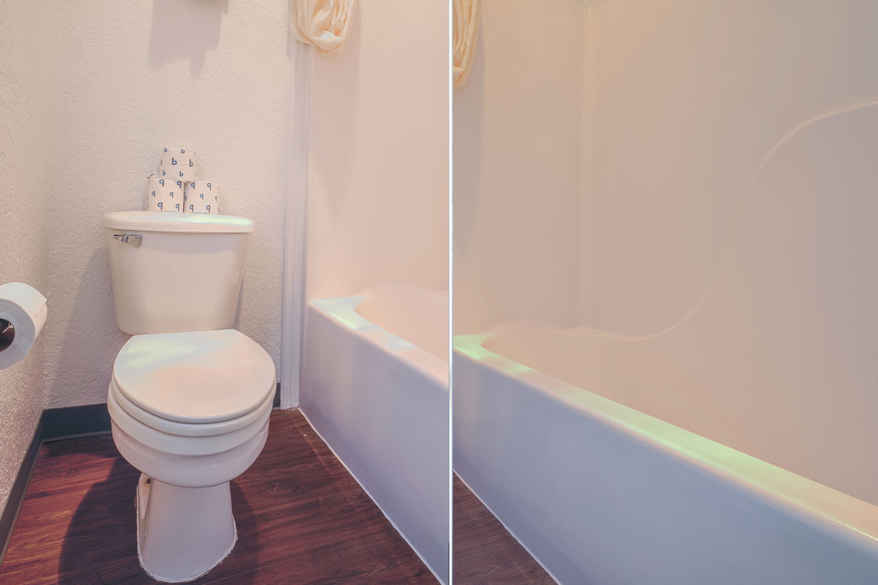 A bathroom with a toilet, a bathtub, and a toilet paper roll.