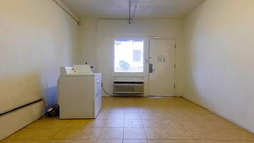 A small, clean room with a washing machine, a door with a window, and a tiled floor.