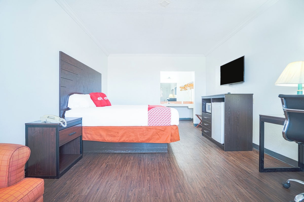 Ein Hotelzimmer mit Bett, Schreibtisch, Stuhl, Fernseher und Lampe.
