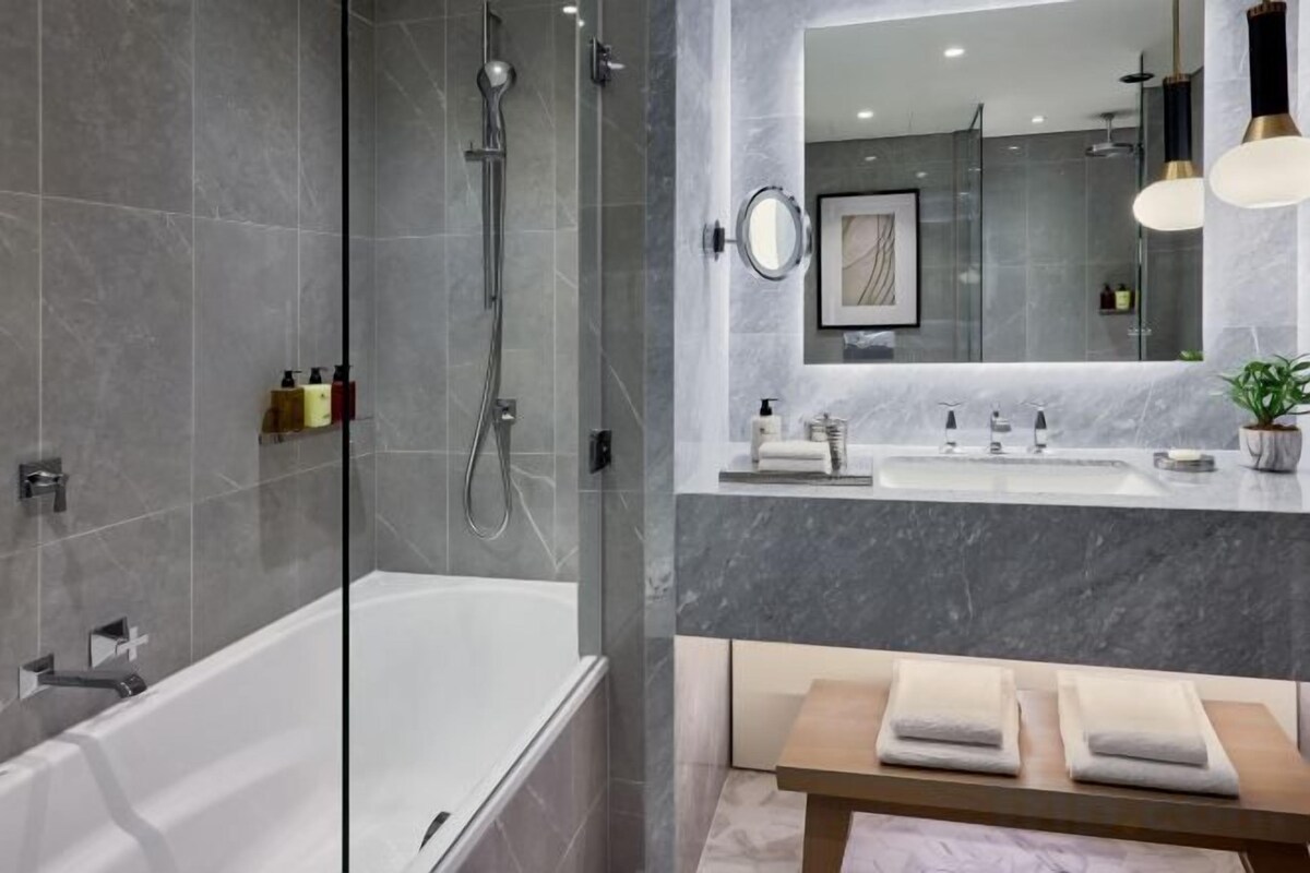 Un bagno moderno con doccia vetrata, una vasca da bagno bianca e un mobile lavabo con specchio e lavandino.