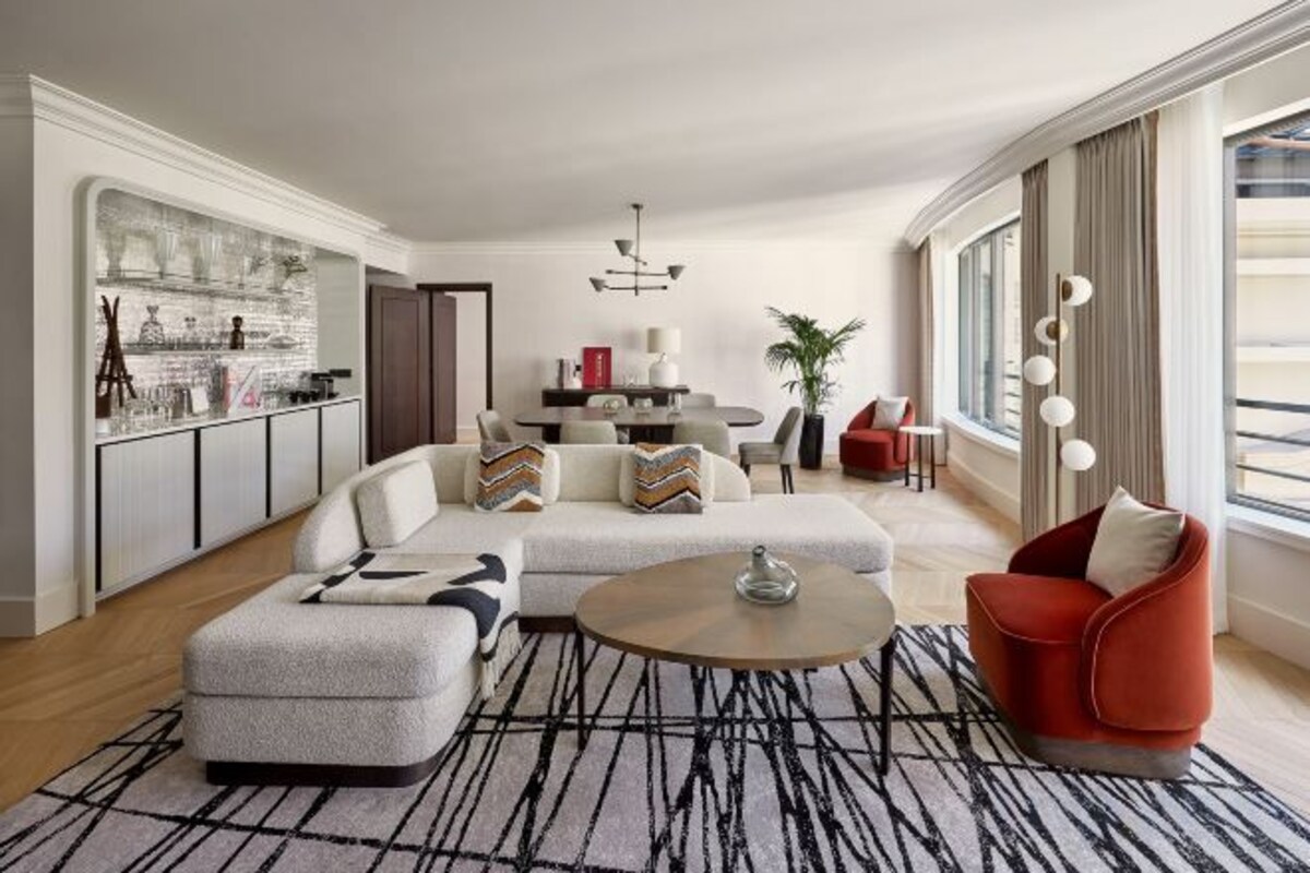 A modern living room with a sectional sofa, a red armchair, a coffee table, and a kitchen area with a bar.