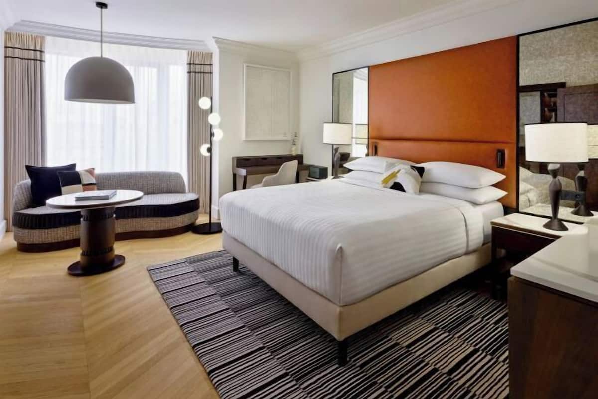 Una habitación de hotel con una cama grande, una mesa redonda, un sofá y un escritorio.
