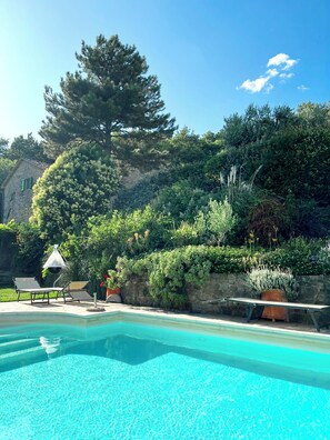 A swimming pool with lounge chairs, surrounded by lush greenery and a stone wall. - Casa Emma, Near Cortona, Private Pool. BBQ, Stunning views, BBand,Relax, enjoy! (Cortona)