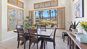 A dining area with a large table, chairs, and a view of palm trees and mountains. - 3 Bed Permit#227096 PGA West, relaxing heated pool home with views! (La Quinta)