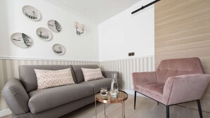 Ett modernt vardagsrum med en grå soffa, en rosa fåtölj och ett runt soffbord.