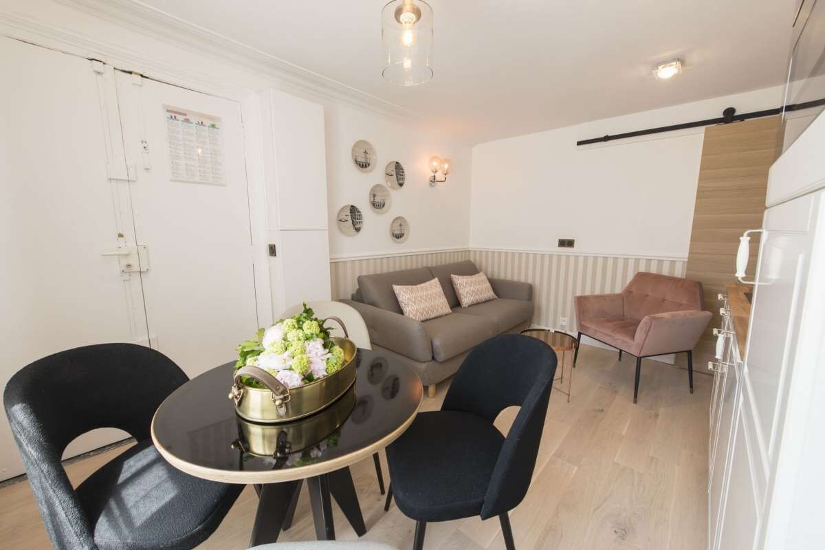 A compact living space with a dining table, two chairs, a sofa, and a pink armchair.