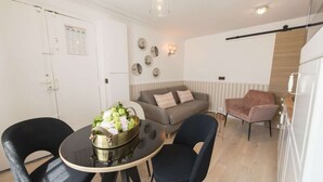 Ett kompakt vardagsrum med ett matbord, två stolar, en soffa och en rosa fåtölj.