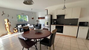 Una cucina moderna con mobili bianchi, un piano cottura nero e un forno a microonde. C'è un'area pranzo con un tavolo rotondo e sedie.