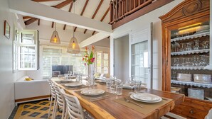 A dining area with a wooden table set for six, white chairs, and a glass cabinet with dishes.