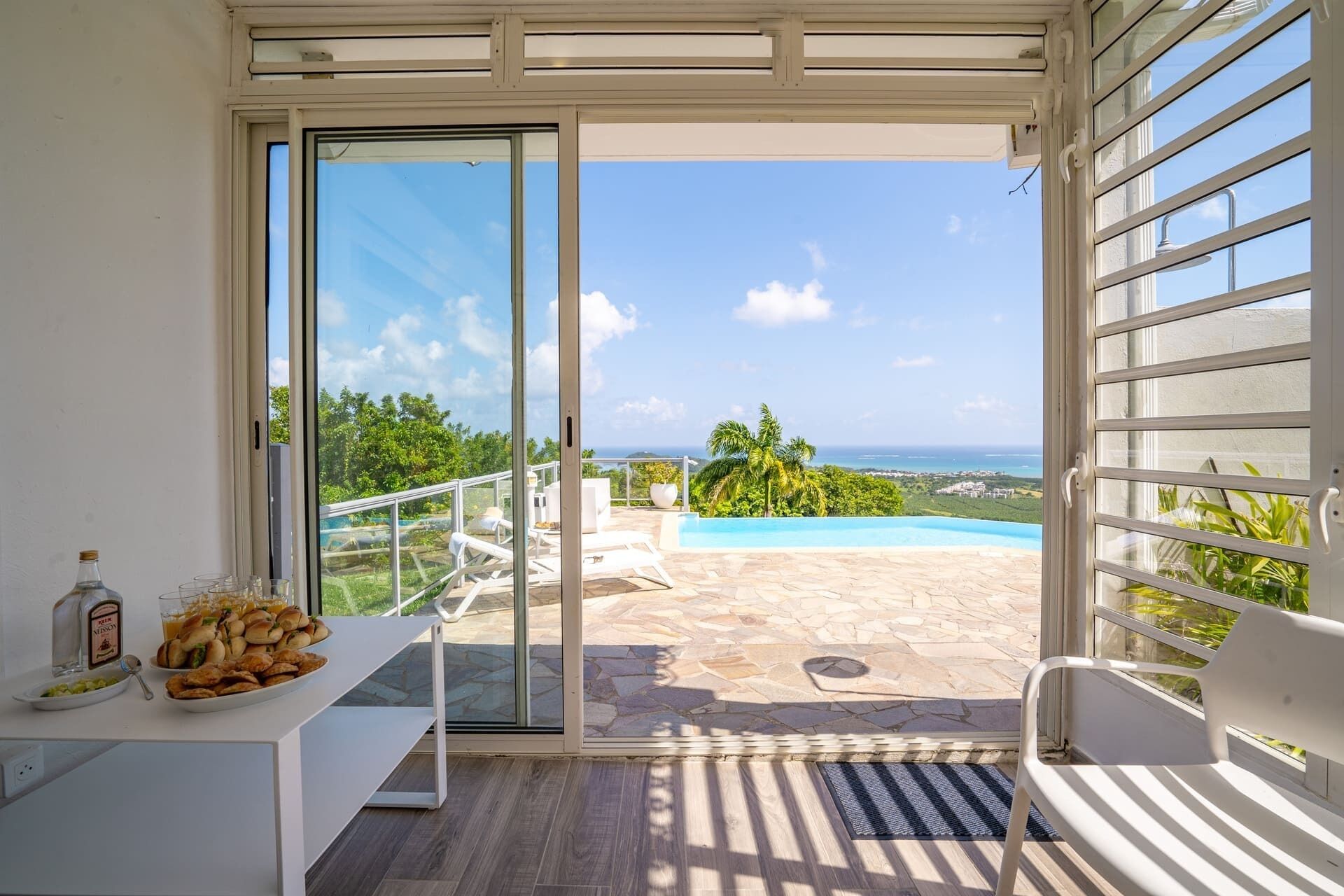 A balcony with a glass door leading to a pool and ocean view.