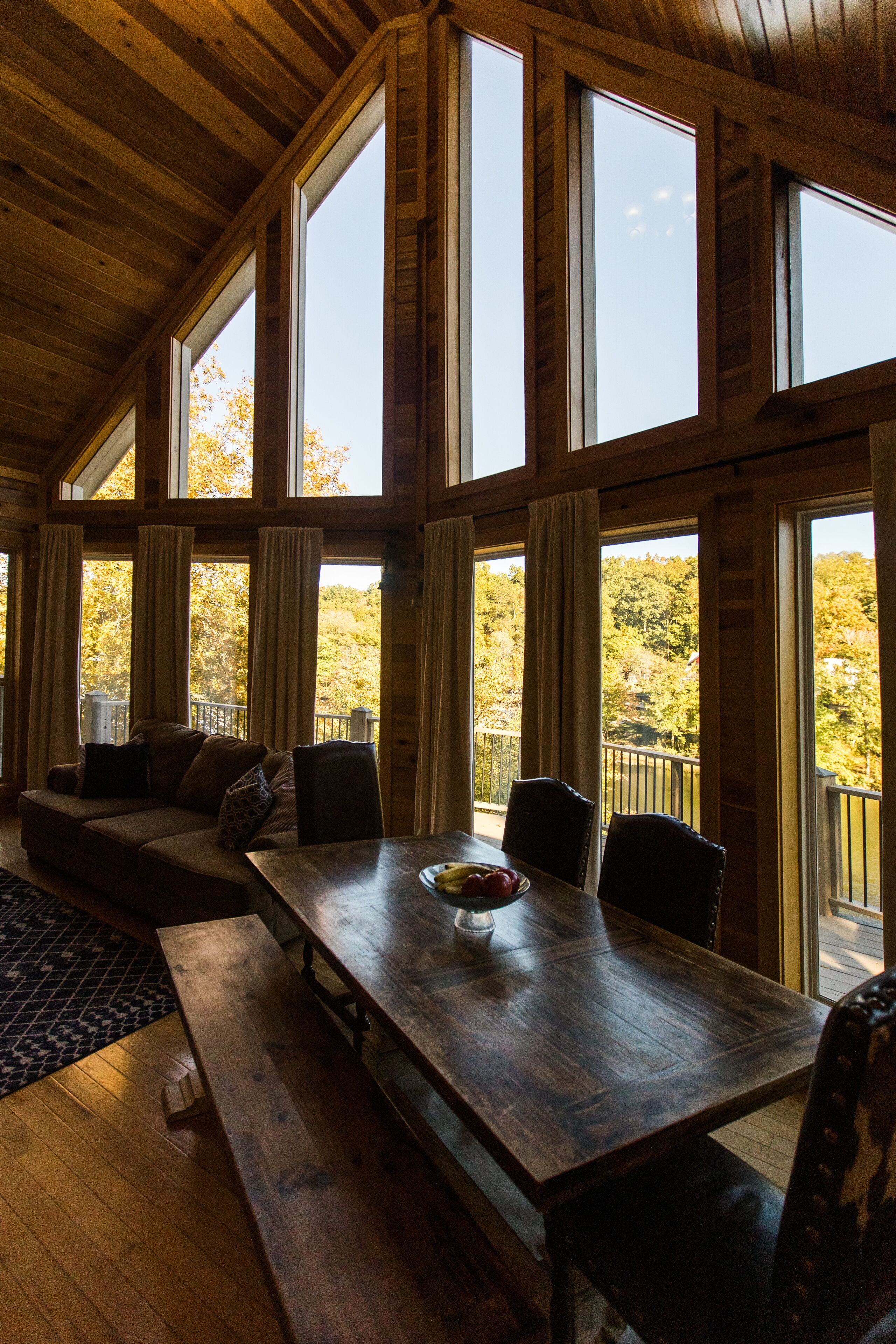 A wooden interior with a large dining table, benches, and a sofa.