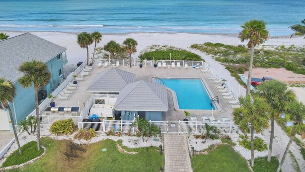 Een resort met zwembad, uitzicht op het strand en palmbomen.