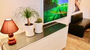 Un salon moderne avec un téléviseur à écran plat, une plante en pot, une lampe et un canapé.