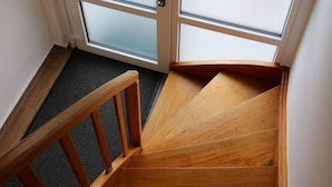 Un escalier en bois mène à une porte dont les panneaux sont en verre dépoli.