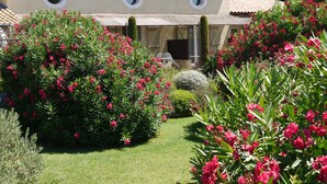 A building with a tiled roof, circular windows, and a well-maintained garden with pink flowers and green shrubs. - 5 bedrooms and suites with 5 bathrooms Charming mas in Maussane les alpilles calm and privacy (Maussane-les-Alpilles)