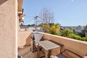 A balcony with a grill, a table, and a chair.