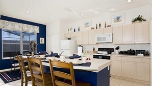 Una cocina moderna con una isla central, armarios blancos y un microondas sobre la encimera.
