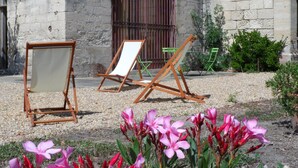 A courtyard with outdoor seating, a stone building, and flowering plants.