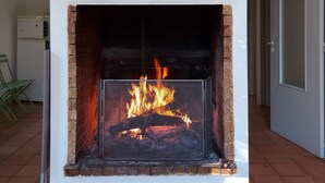 A fireplace with a metal screen and a brick surround, a white wall above it, and a tiled floor.
