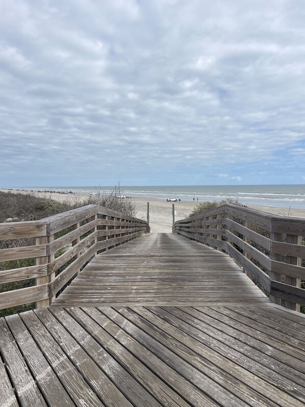 A wooden boardwalk leading to a beach with a cloudy sky. - Why Rent The Rest When You Can Have The Best? (Port Aransas)